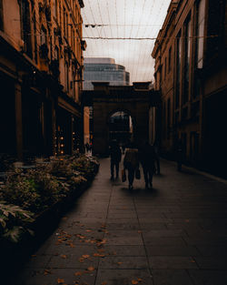 People walking on footpath amidst buildings in city