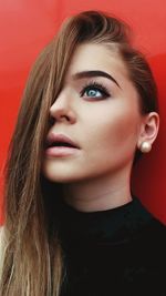 Close-up portrait of a beautiful young woman over red background