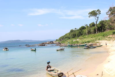 Boats moored on shore at beach against sky