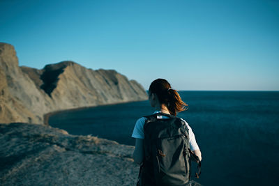 Rear view of woman looking at sea against clear blue sky