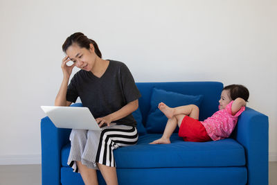 Young woman using phone while sitting on sofa at home