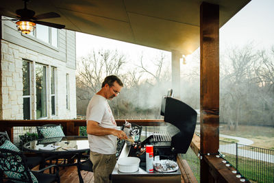 Man cooking food on barbeque at porch