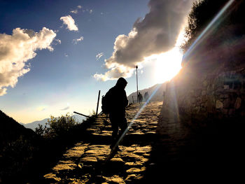 Rear view of silhouette man walking against bright sun