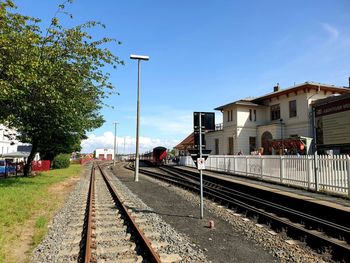 Railroad tracks by street against sky