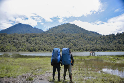 Rear view of men standing on mountain against sky
