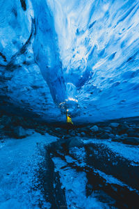 Man with torch light under ice cave