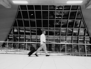 Rear view of a man walking on tiled floor in building
