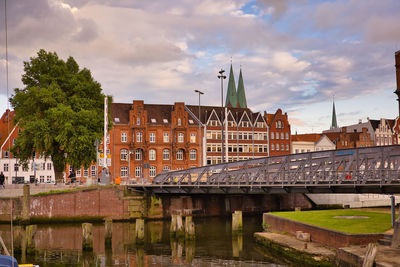 Bridge over river by buildings against sky