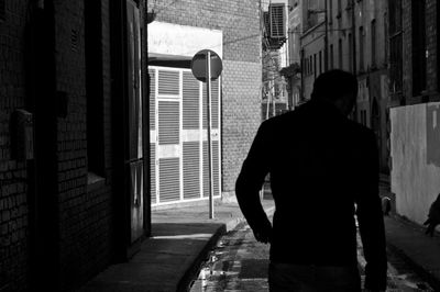 Rear view of a man walking down alley