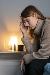 Cute girl sitting on bed and holding her head. woman suffering from headache or migraine.