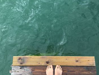 Low section of person standing on pier over sea