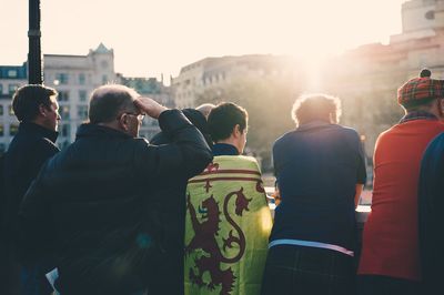 Rear view of people standing in city against sky