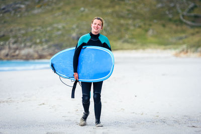 Portrait of surfer woman with surfboard standing at beach