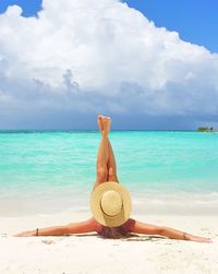 Woman relaxing at beach against sky