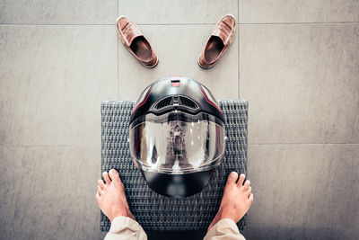 Low section of man standing by helmet on mat