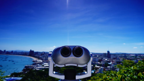 Close-up of coin-operated binoculars against cityscape