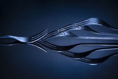 Close-up of forks arranged on table against blue background