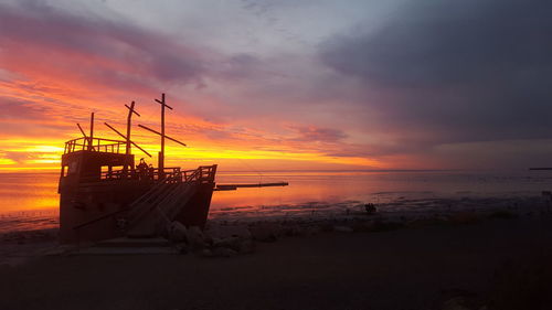 Sailboat moored on sea against sky during sunset