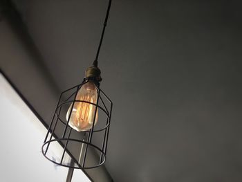 Low angle view of illuminated lamp against wall