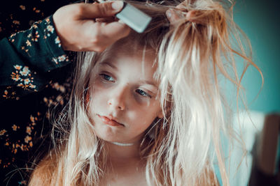 Cropped hand of mother combing daughter hair at home