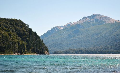 Scenic view of sea and mountains against clear sky