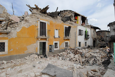 Abandoned house by building against sky