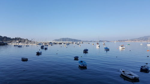 Boats in sea against clear blue sky