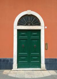 Italian green old-fashioned door on orange wall