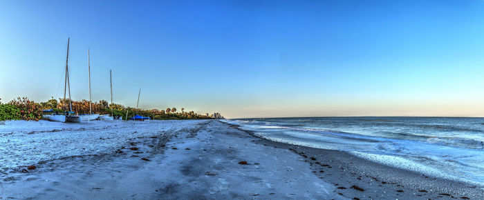 Scenic view of beach against clear blue sky during winter