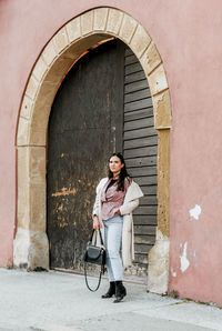 Full length of woman standing against wall