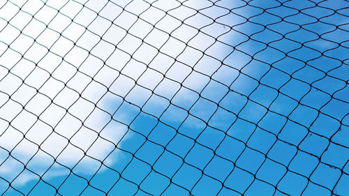 Full frame shot of chainlink fence against blue sky