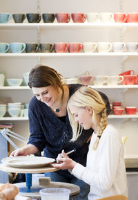 Smiling woman and girl making pottery plate