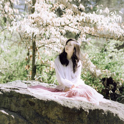 Portrait of smiling young woman sitting on rock