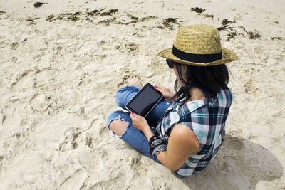 Pretty girl using digital tablet on the beach