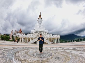 Full length of man standing at walkway against buddha statues