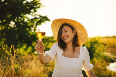 Young beautiful girl in a white dress having a picnic with a glass of champagne or white wine
