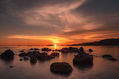 Scenic view of rocks in sea against sky during sunset