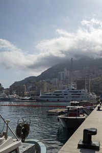 Sailboats moored at harbor by city against sky