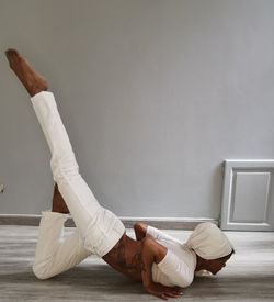 Low section of man sitting on floor against wall