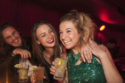 Smiling young woman drinking water from glass at night