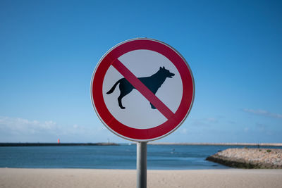 Close-up of information sign on beach against clear sky