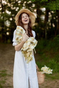 Portrait of young woman standing against trees