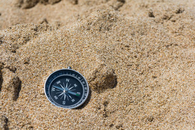 High angle view of navigational compass on sand