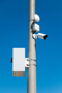 Low angle view of telephone pole against clear blue sky