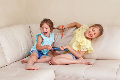 Siblings arguing while sitting on sofa at home