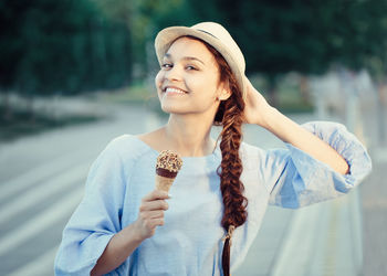 Portrait of smiling young woman holding hat