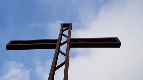 Low angle view of cross on pole against sky