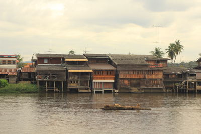 Buildings by river against sky