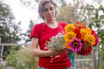 A woman gardener holds out a bright bouquet of wildflowers