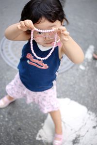 Portrait of girl holding camera while standing outdoors